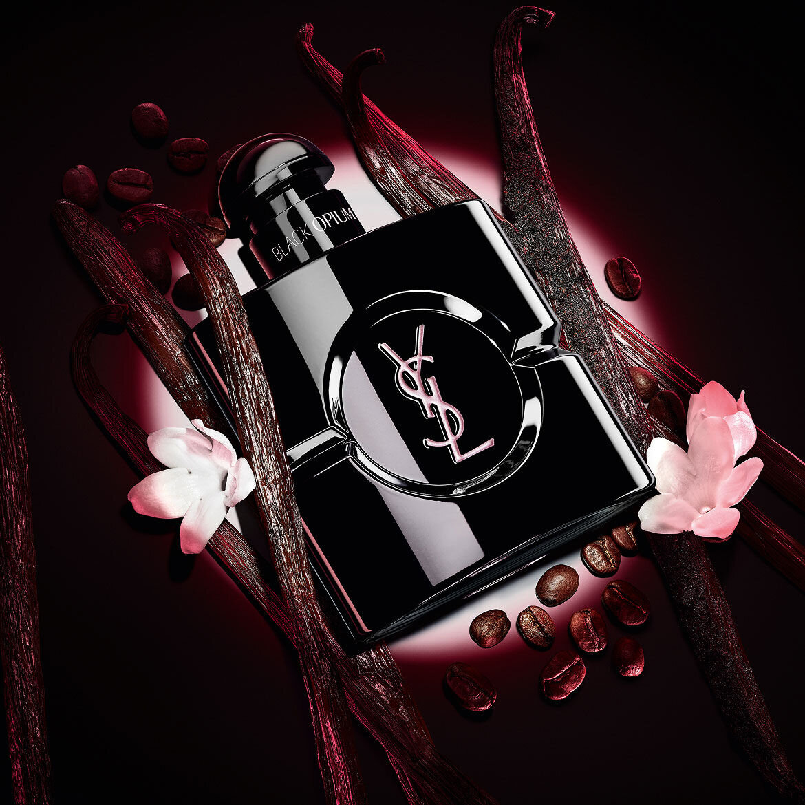 Black Opium Le Parfum-flacon in glanzend zwart, omringd door donkere vanillepeulen en witte jasmijn.