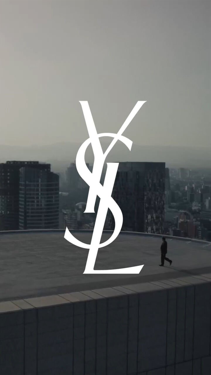 YSL-logo boven een dakterras met skyline bij zonsondergang