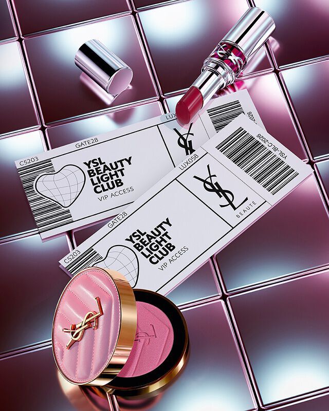 Loveshine lippenstift in de kleur Make Me Blush en twee VIP-tickets voor de YSL Beauty Light Club op een reflecterende tegelachtergrond.