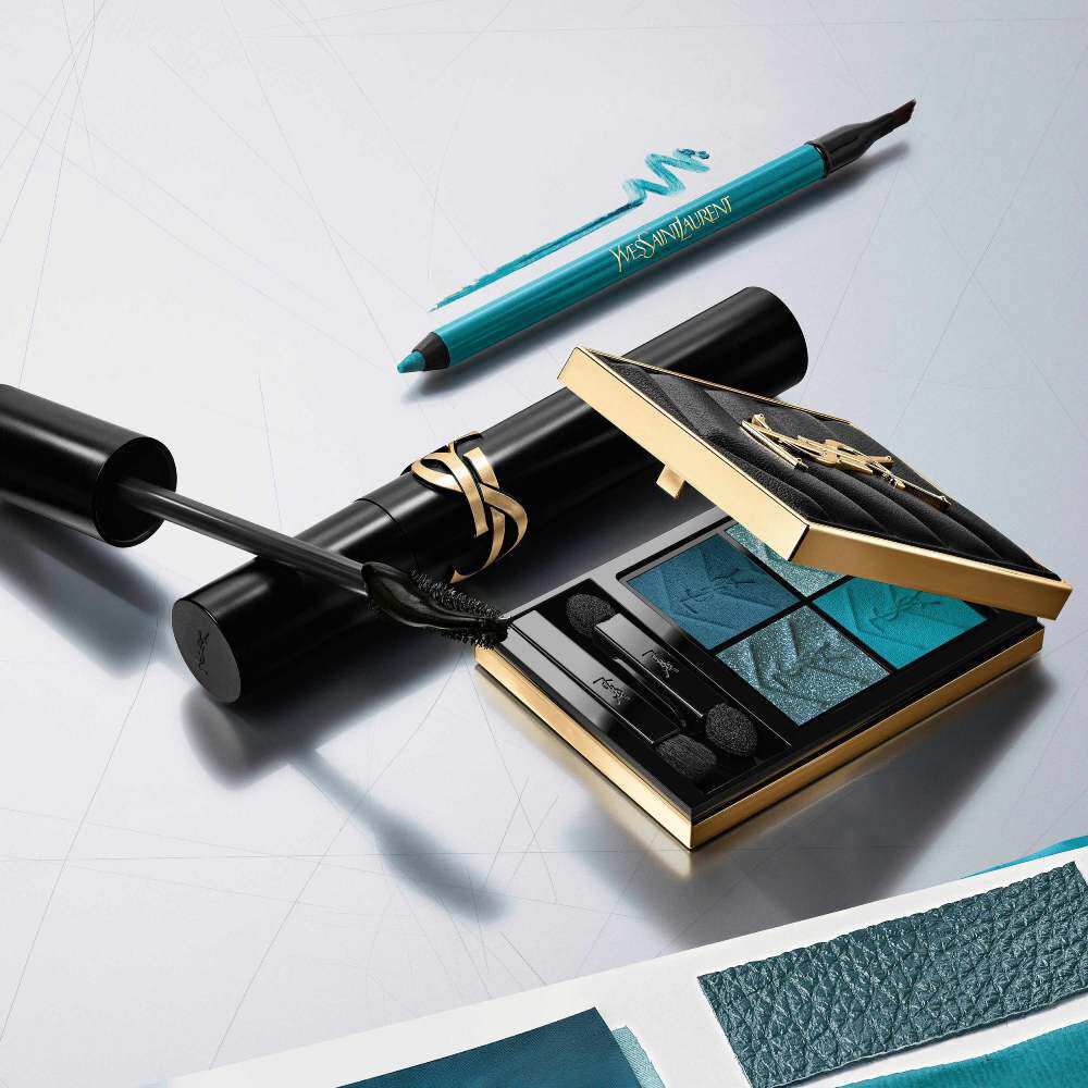 Luxe YSL make-up collectie: blauw oogschaduwpalet, mascara en eyeliner op een zilveren achtergrond.