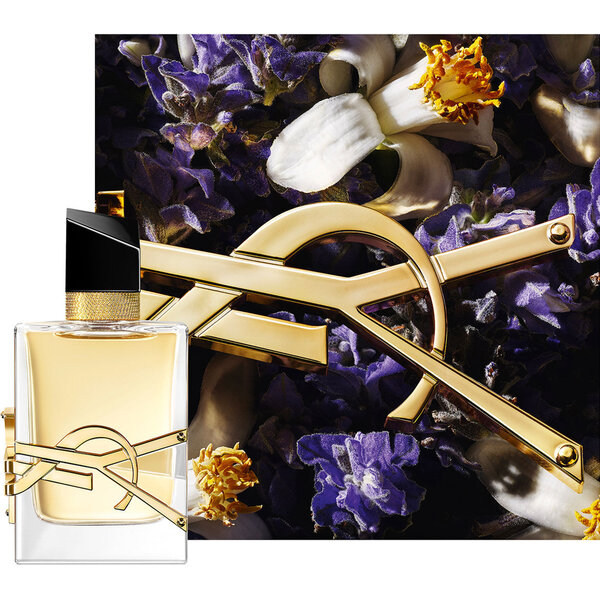 Libre Eau de Parfum-flacon met gouden ketting en paarse bloemen tegen een donkere achtergrond.