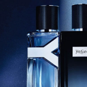 A close-up of two elegant perfume bottles against a dark blue background, showcasing sleek designs and one featuring the Yves Saint Laurent logo.