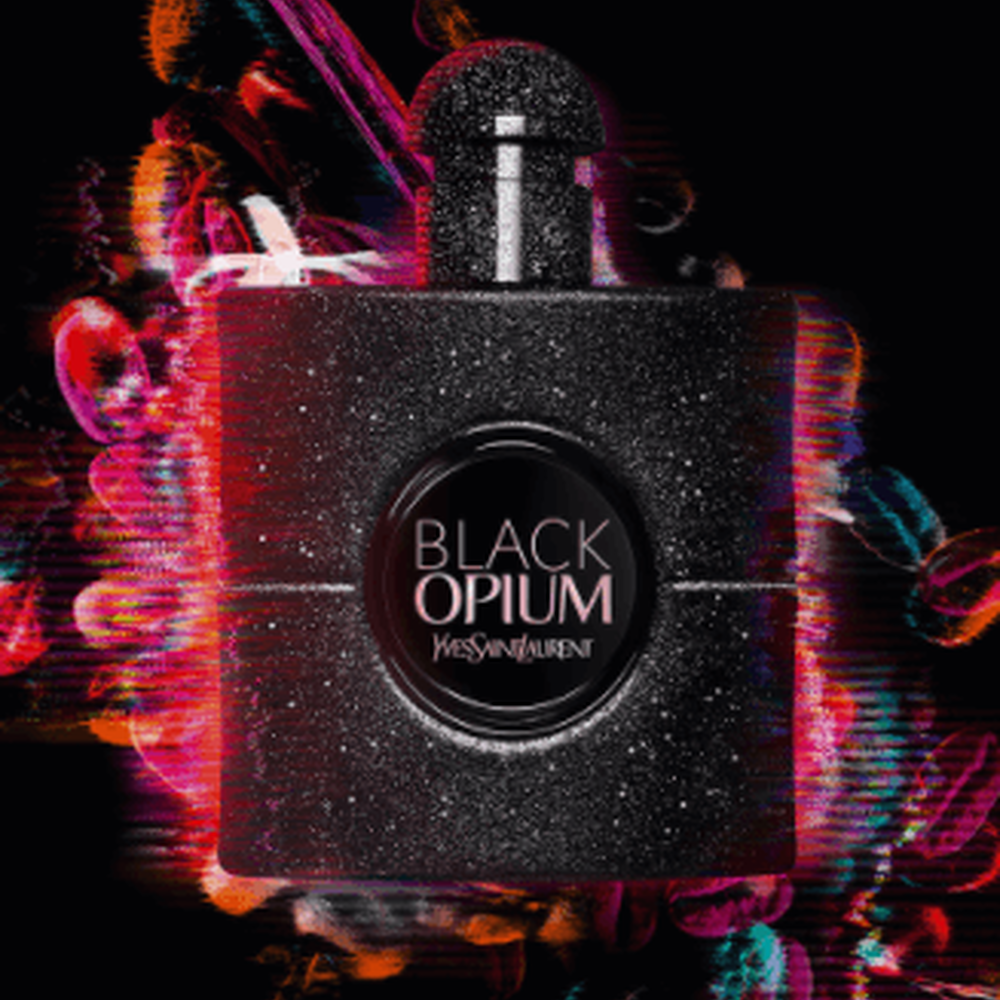 A black glittery perfume bottle labeled "Black Opium" by Yves Saint Laurent, surrounded by colorful, abstract light effects on a dark background.