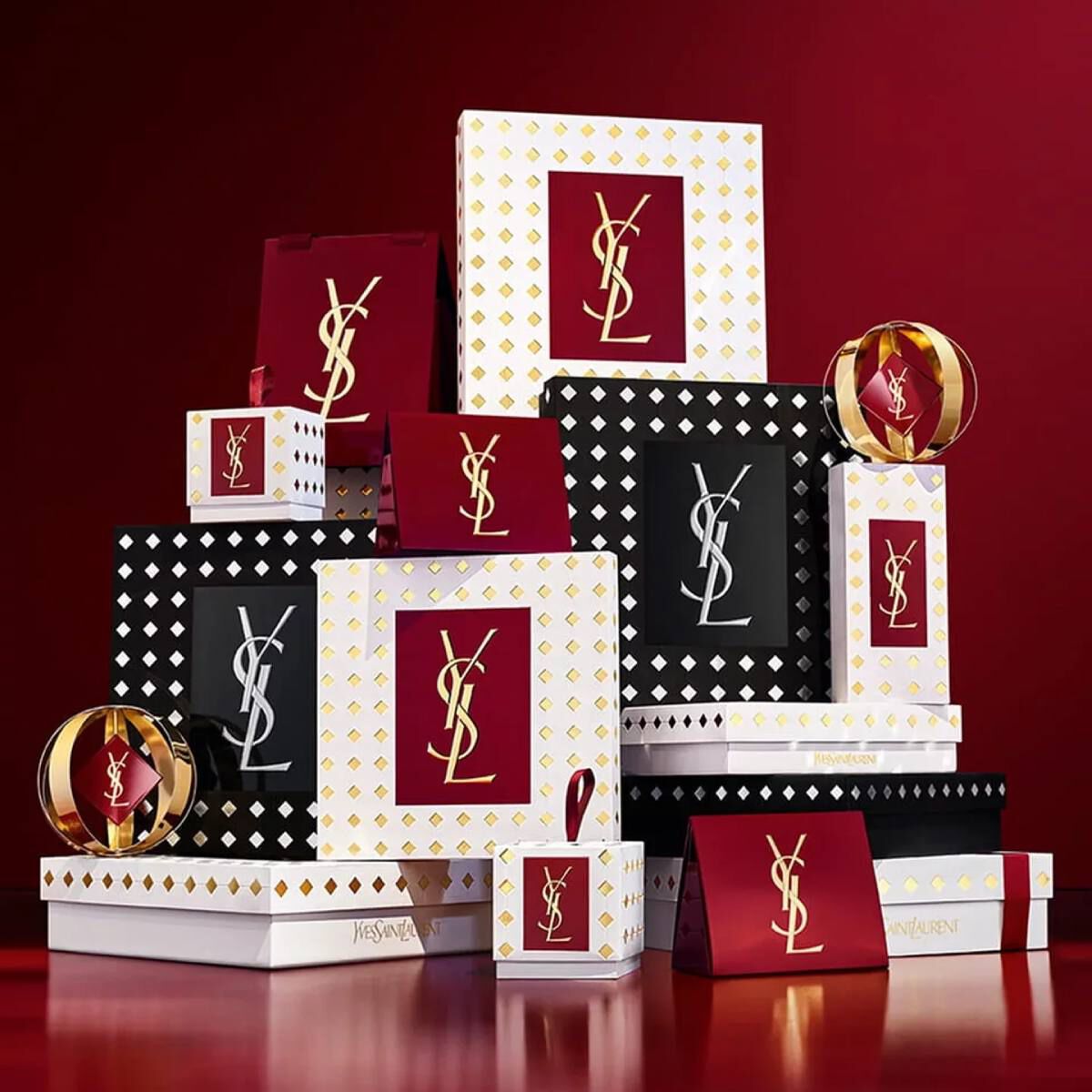 Yves Saint Laurent kerstcollectie cadeausets en luxe schoonheidsproducten tegen een feestelijke rode achtergrond.