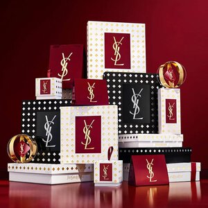 Yves Saint Laurent kerstcollectie cadeausets en luxe schoonheidsproducten tegen een feestelijke rode achtergrond.
