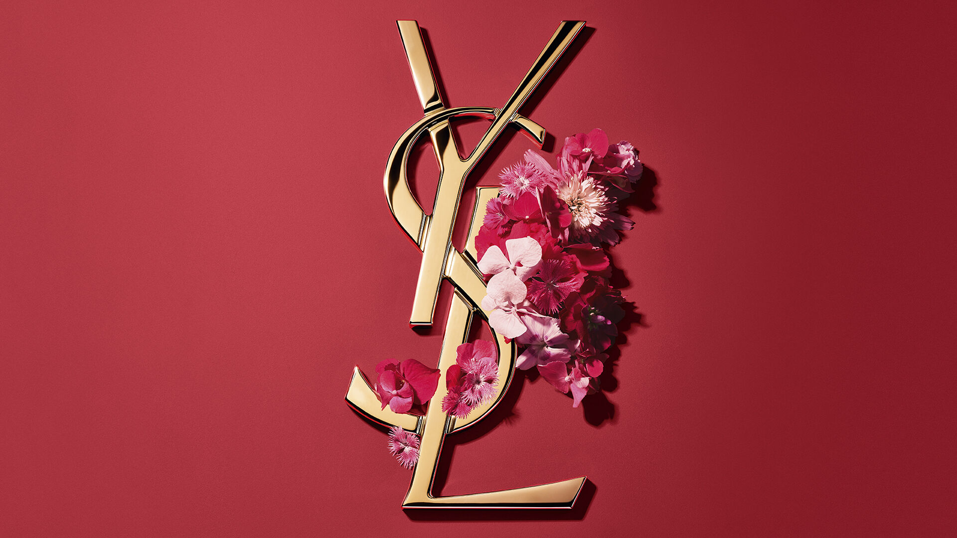 Rode YSL geschenkdoos met roze bloemen op een rode achtergrond.