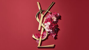 Rode YSL geschenkdoos met roze bloemen op een rode achtergrond.