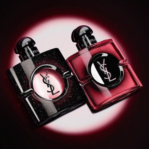 Twee verlichte Yves Saint Laurent Black Opium parfumflacons tegen een donkere achtergrond.