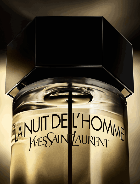 A dark bottle of Yves Saint Laurent's "La Nuit de L'Homme" fragrance, positioned in soft light with a shadowed background, highlighting its sleek design.