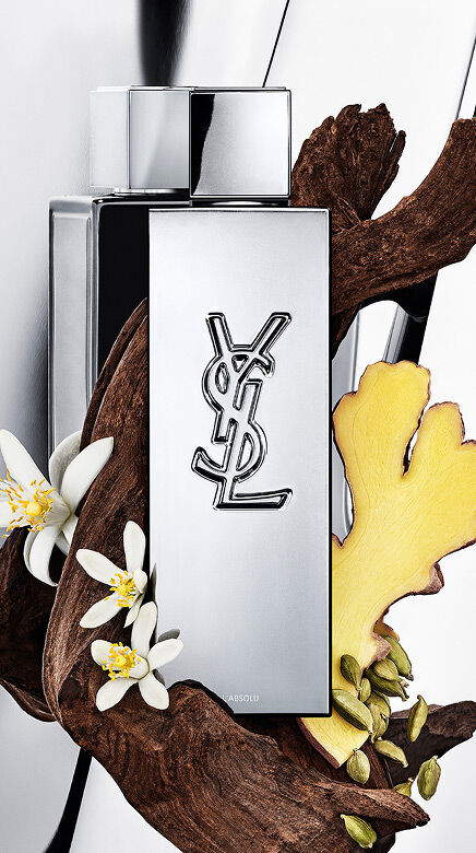 YSL Y L'ABSOLU parfumfles omringd door donker hout, witte oranjebloesem, gember en kardemompeulen.
