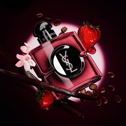 YSL Black Opium parfumflacon omringd door koffiebonen, aardbeien, vanillestokjes en witte bloemen op een donkere achtergrond.