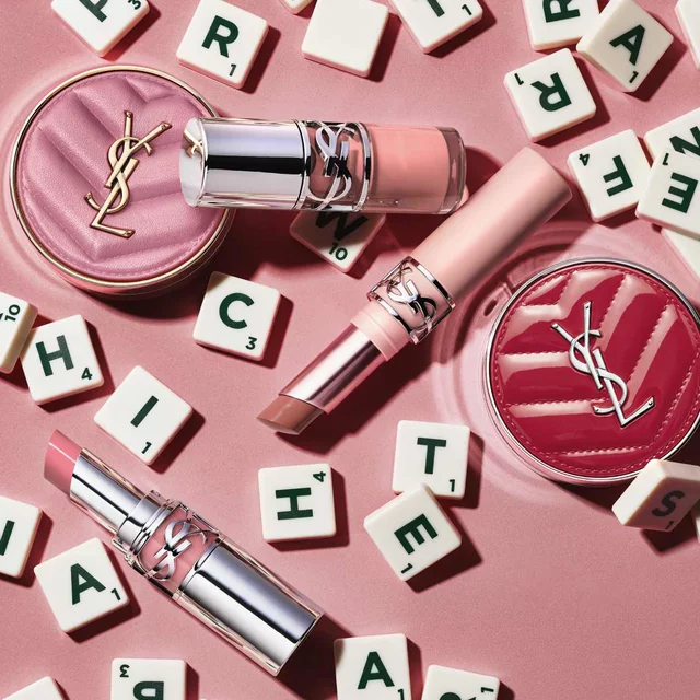 YSL-make-upproducten en lettersteentjes op een roze achtergrond.