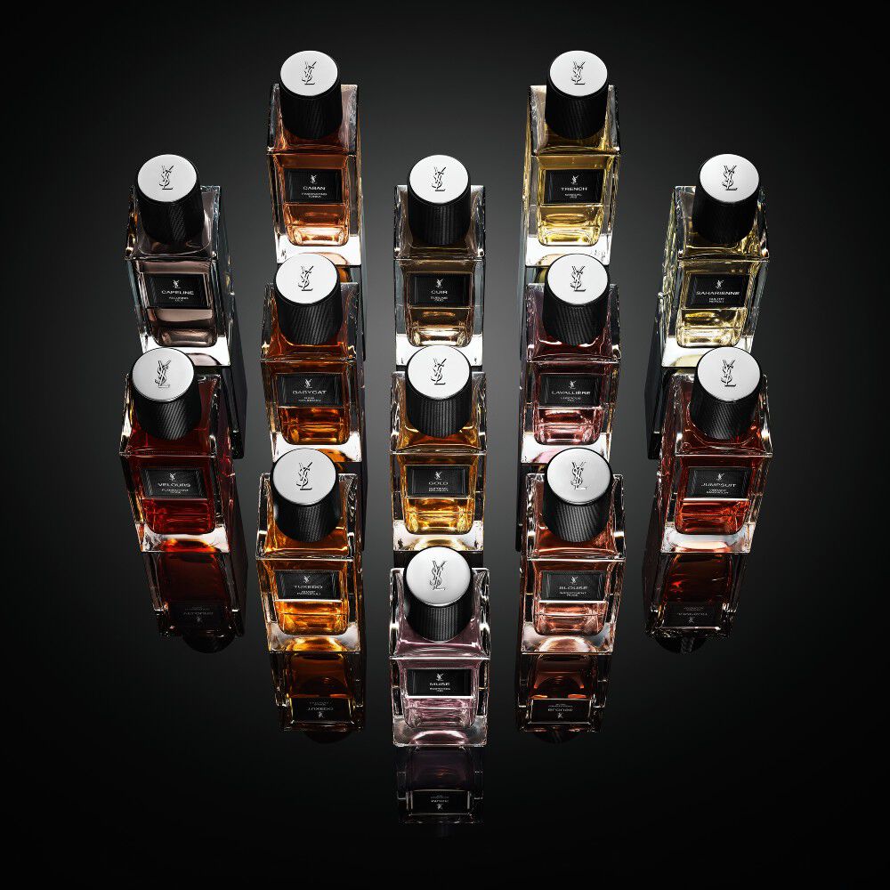 Een collectie Yves Saint Laurent "Le Vestiaire des Parfums" geurflacons gerangschikt in een ruitvorm op een reflecterend zwart oppervlak.