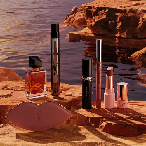 YSL-make-up, parfums en een witte pouch in een zonnige woestijn.