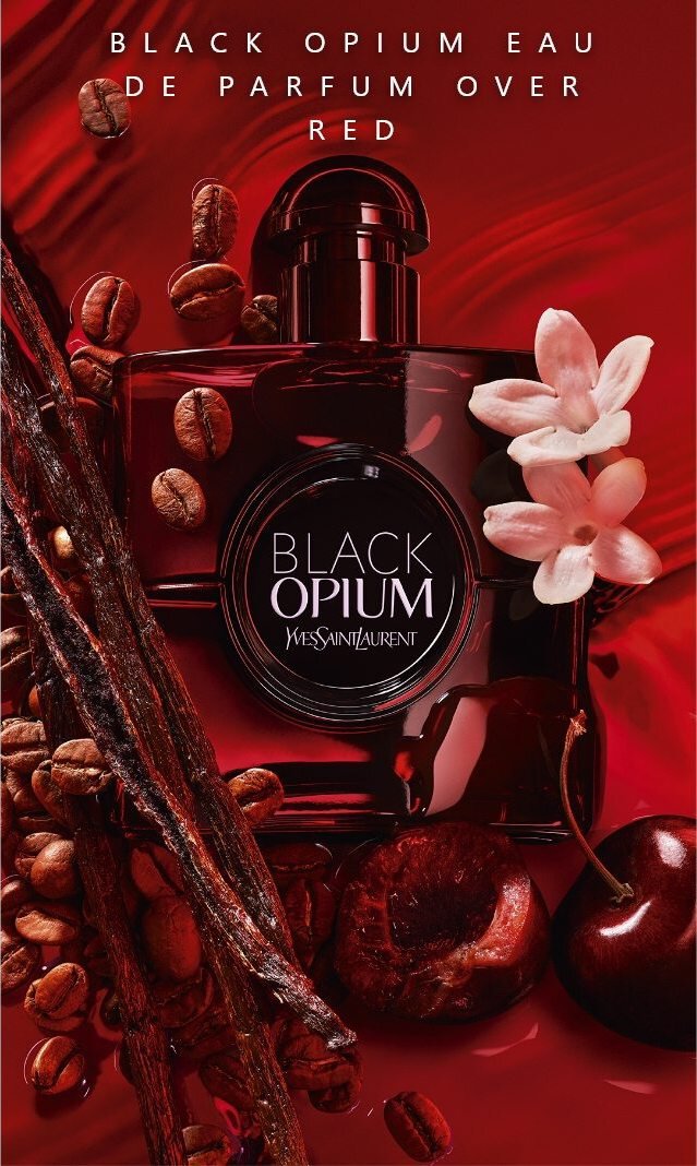 Een flacon Black Opium parfum van Yves Saint Laurent omgeven door koffiebonen, vanille-stokken en witte bloemen op een rode achtergrond.