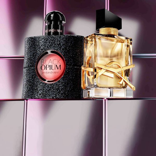 YSL beautyproducten waaronder een doorgestikt compactpoeder, mascara en twee lipsticks tegen een glanzende roze tegelachtergrond.