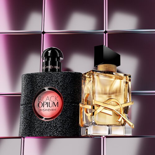 YSL-geurflacons op een sokkel tegen een woestijnlandschap.