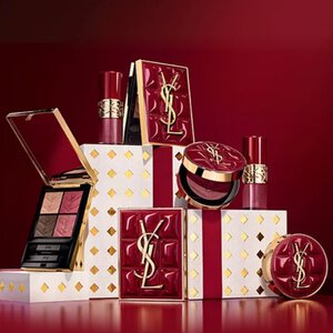 Yves Saint Laurent kerstcollectie cadeausets en luxe schoonheidsproducten tegen een feestelijke rode achtergrond.