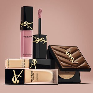 YSL-beautyproducten met blush, foundation en compacte poeder op een nude achtergrond.