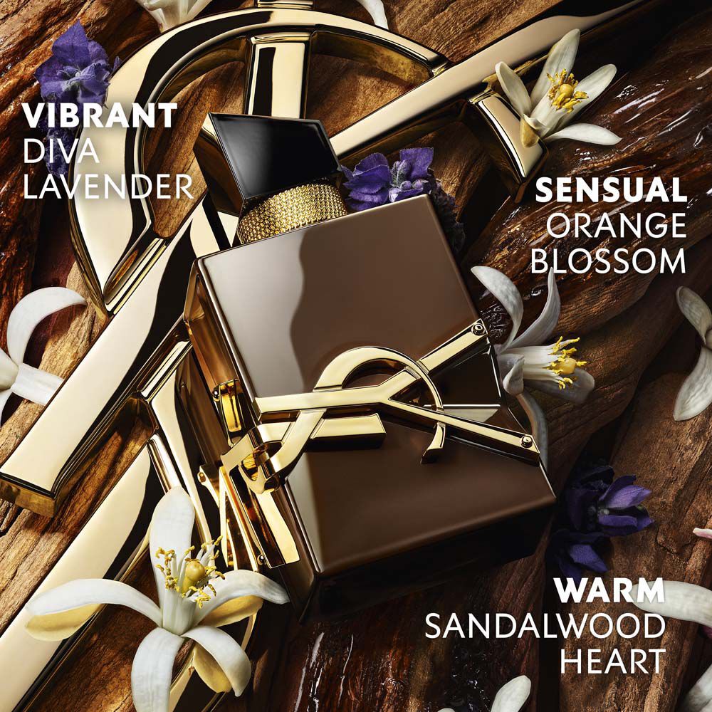 The YSL Cassandre gold rests on raw sandalwood, adorned with white orange blossoms and lavender, with text evoking the sensuality, vibration and energy of sandalwood.