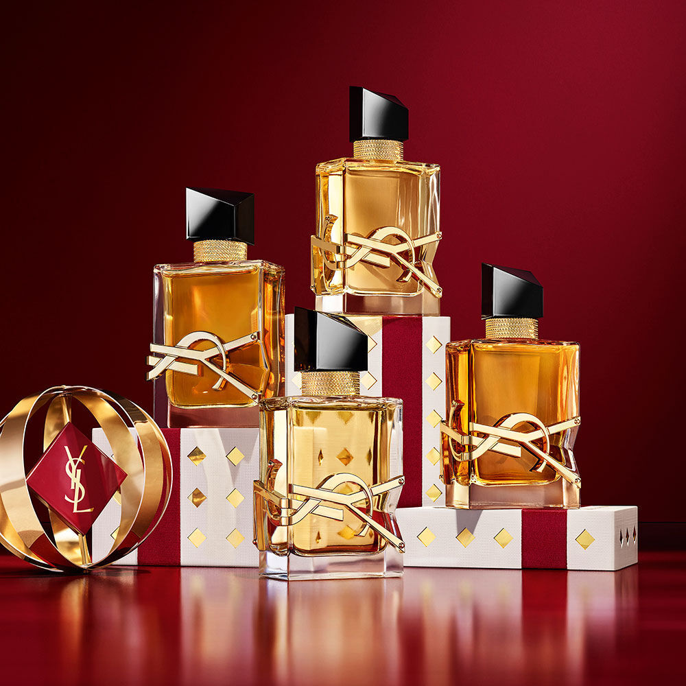 Meerdere YSL LIBRE-flesjes gelaagd over luxe gouden feestverpakking met patina.