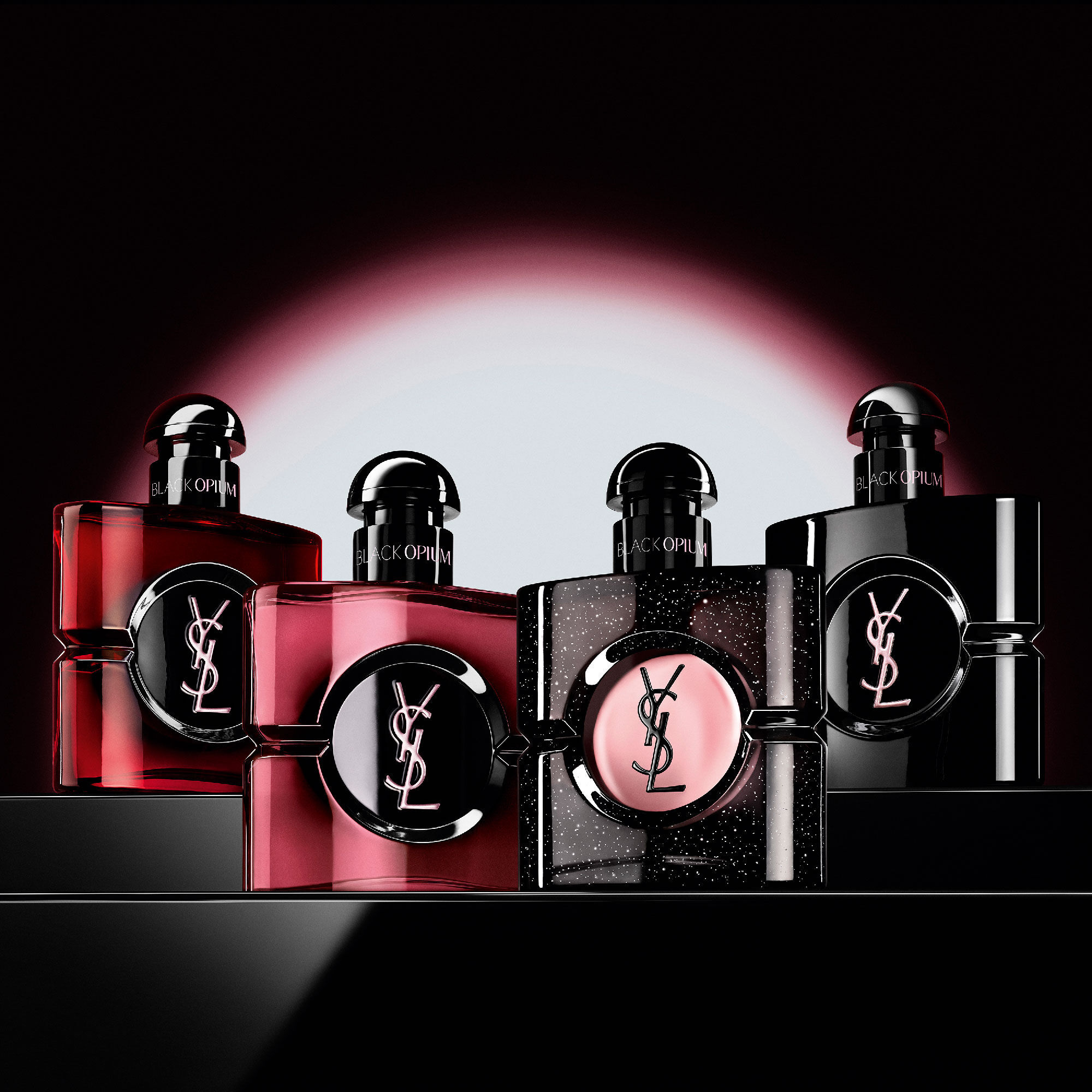 Vier verschillende Black Opium-parfumflacons op een rij op
                        een donker, reflecterend oppervlak.