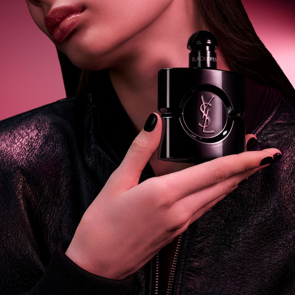 Black Opium Le Parfum-flacon in glanzend zwart, omringd door donkere vanillepeulen en witte jasmijn met claims.