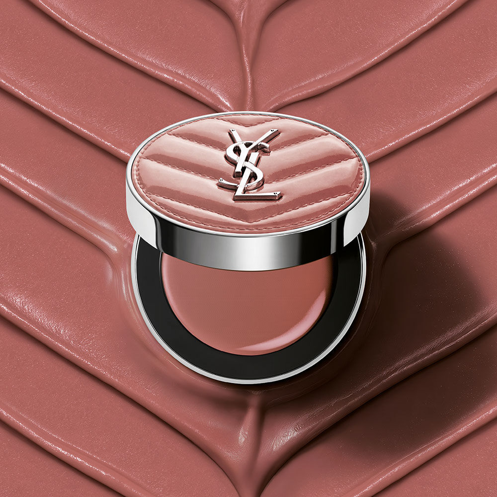 Een open YSL Make Me Blush Lifted Glow Cream Blush compact in tint #44 Nude Lavalliere op een bijpassende roze textuurcreme achtergrond.