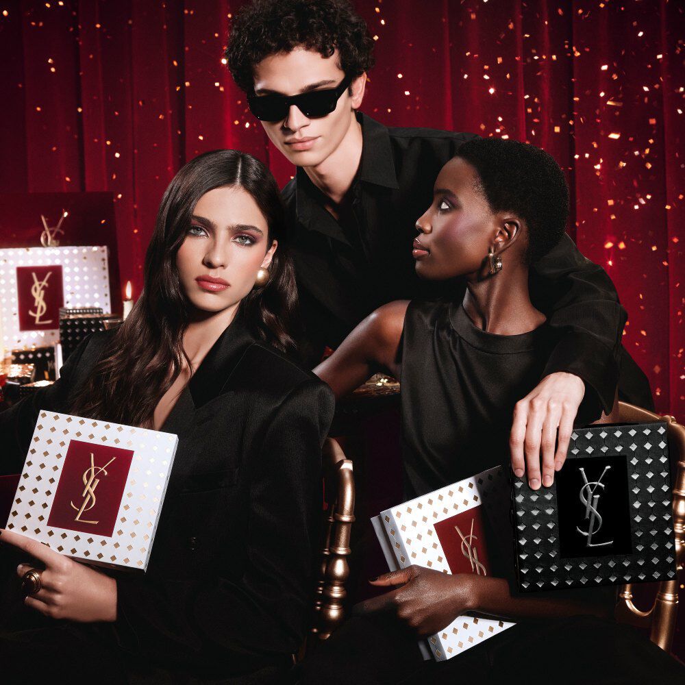 Modellen die samen poseren, luxe YSL Holiday cadeauverpakkingen vasthoudend in een feestelijke sfeer.