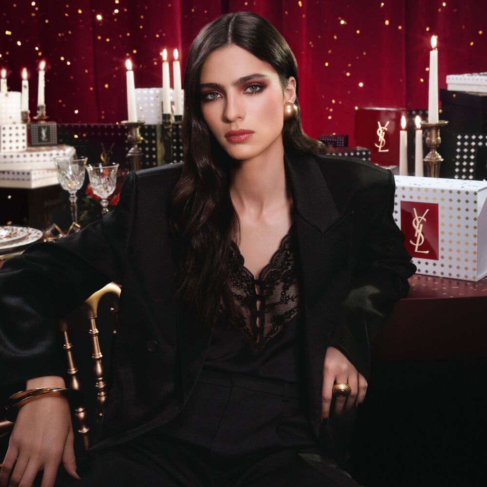 Model in een zwart pak en glamoureuze look, gezeten in een feestelijke kaarsverlichte setting met YSL cadeauverpakkingen.
Model in een zwart pak en glamoureuze look, gezeten in een feestelijke kaarsverlichte setting met YSL cadeauverpakkingen.
Model in een zwart pak en glamoureuze look, gezeten in een feestelijke kaarsverlichte setting met YSL cadeauverpakkingen.