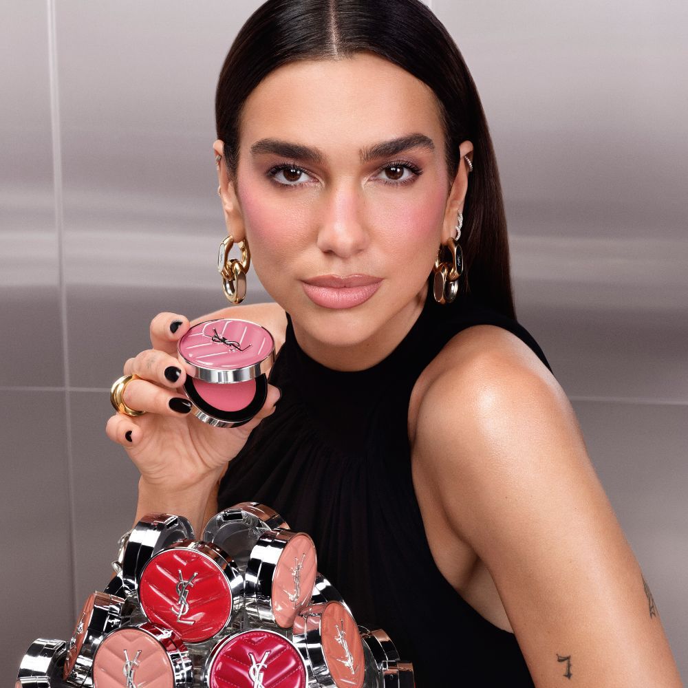 Dua Lipa houdt een open YSL Make Me Blush Lifted Glow Cream Blush compact vast, met een collectie van de nieuwe tinten uitgestald voor haar.