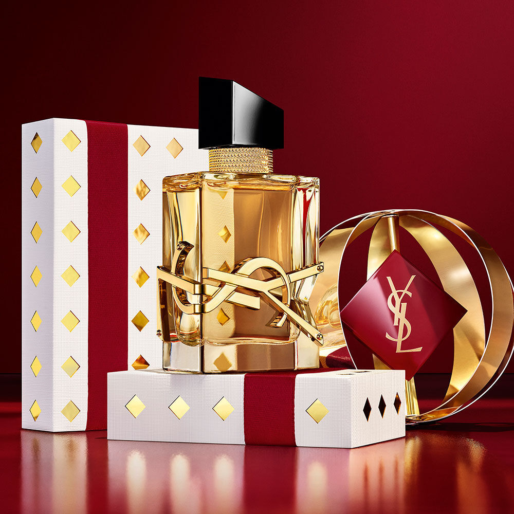 Het iconische LIBRE-flesje, samen met luxe bordeauxrode en gouden YSL cadeauverpakkingen.