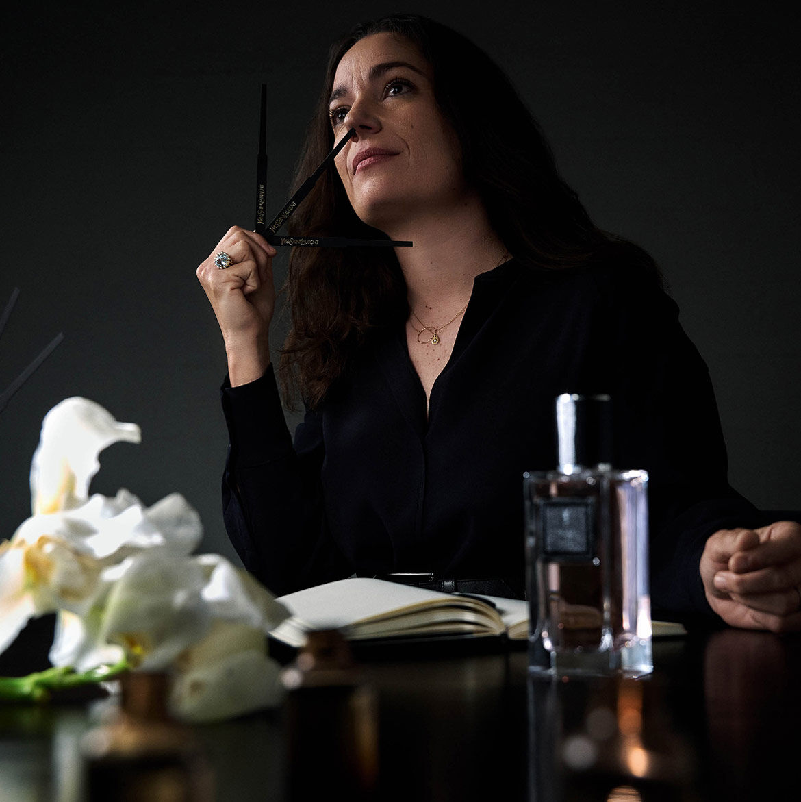 Vrouw ruikt aan parfumstrips, met een notitieboek en een parfumfles.