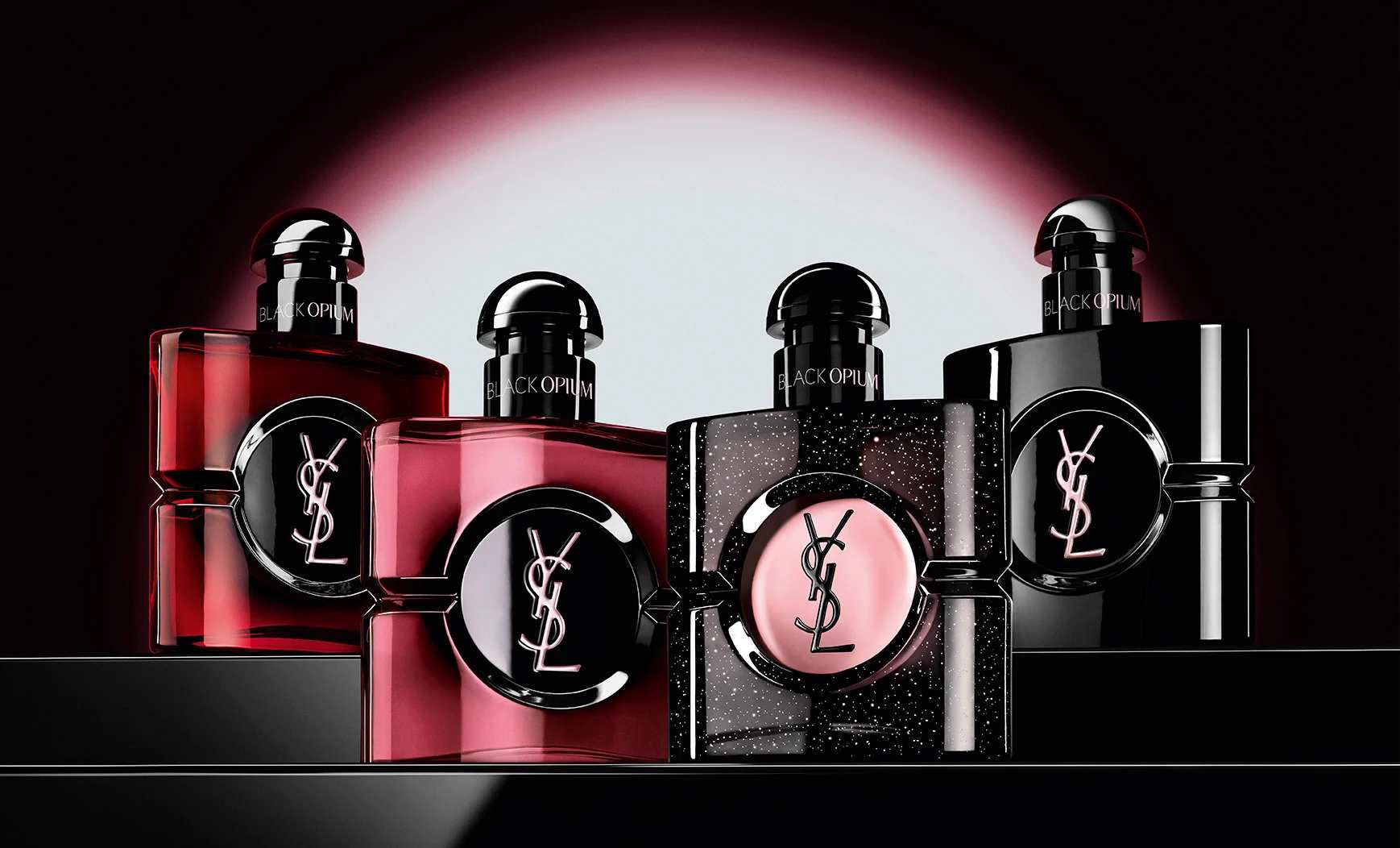 Vier verschillende Black Opium-parfumflacons op een rij op een donker, reflecterend oppervlak.