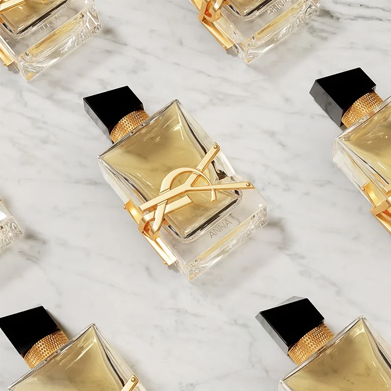 Gepersonaliseerde YSL Libre parfumflacons met gegraveerde namen, gepresenteerd op wit marmer.