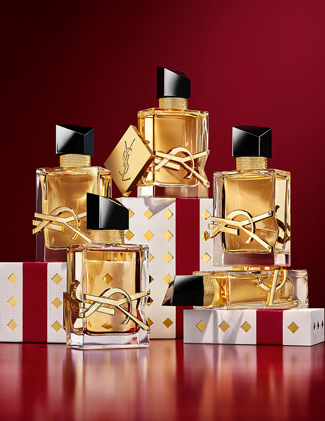 Multiple YSL LIBRE fragrance bottles layered over luxury gold-patterned Holiday gift packaging.
