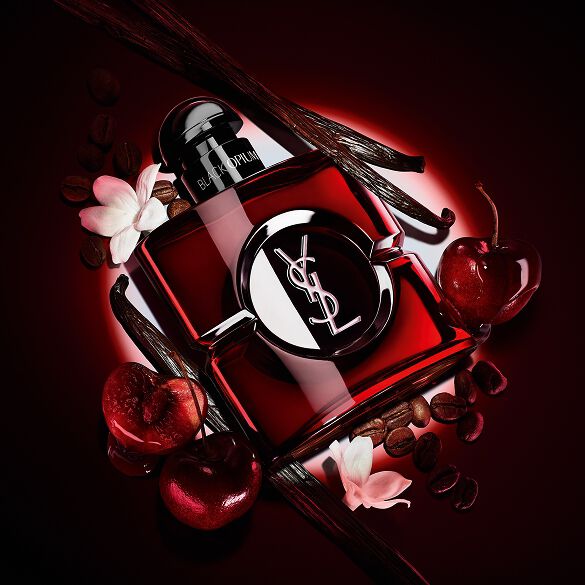 Black Opium Over Red-flacon in dieprode lak, omringd door verse rode kersen en gebrande koffiebonen.