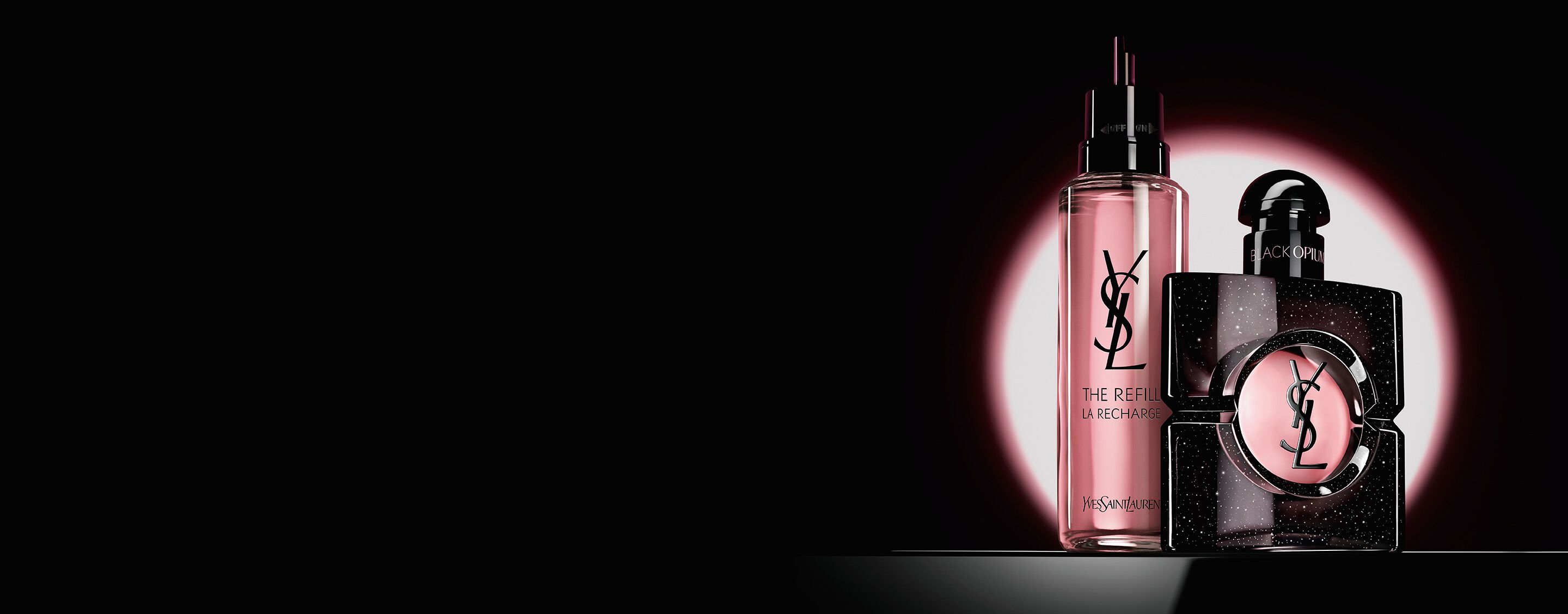 Flacon van Black Opium Eau de Parfum naast de glazen navulflacon van 100 ml met het YSL-logo.