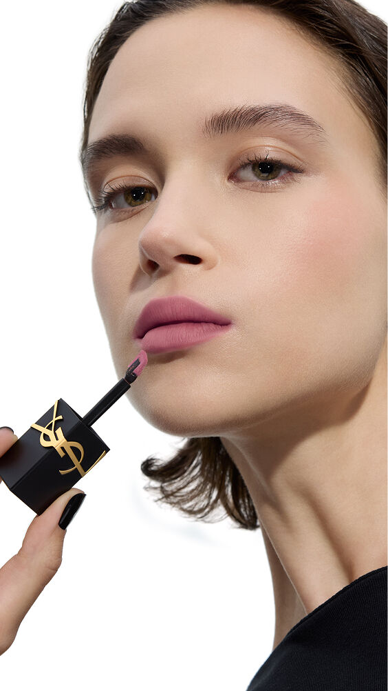 Model met een lichte huidskleur brengt een koele, zachte mauve tint van YSL THE INKS BLUR lippenvlek aan met de applicator.