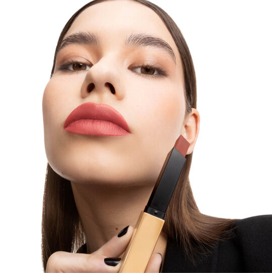 Hand houdt een gesloten zwart‑gouden YSL-lipstick.