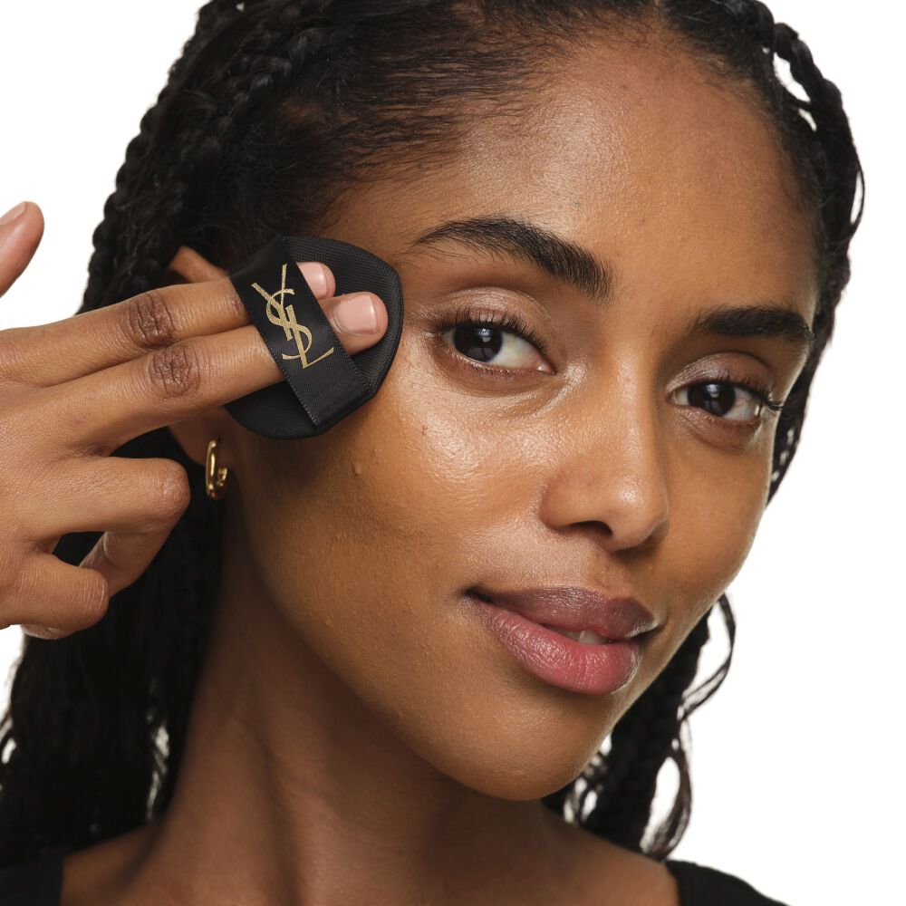 Close-up die laat zien hoe je YSL SKIN AFFAIR CUSHION op de wang aanbrengt voor een naadloze, opbouwbare en stralende dekking.