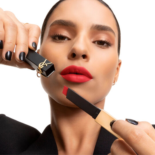 Hand toont een YSL-lipstick met vierkante punt in zacht roze naast de wang.