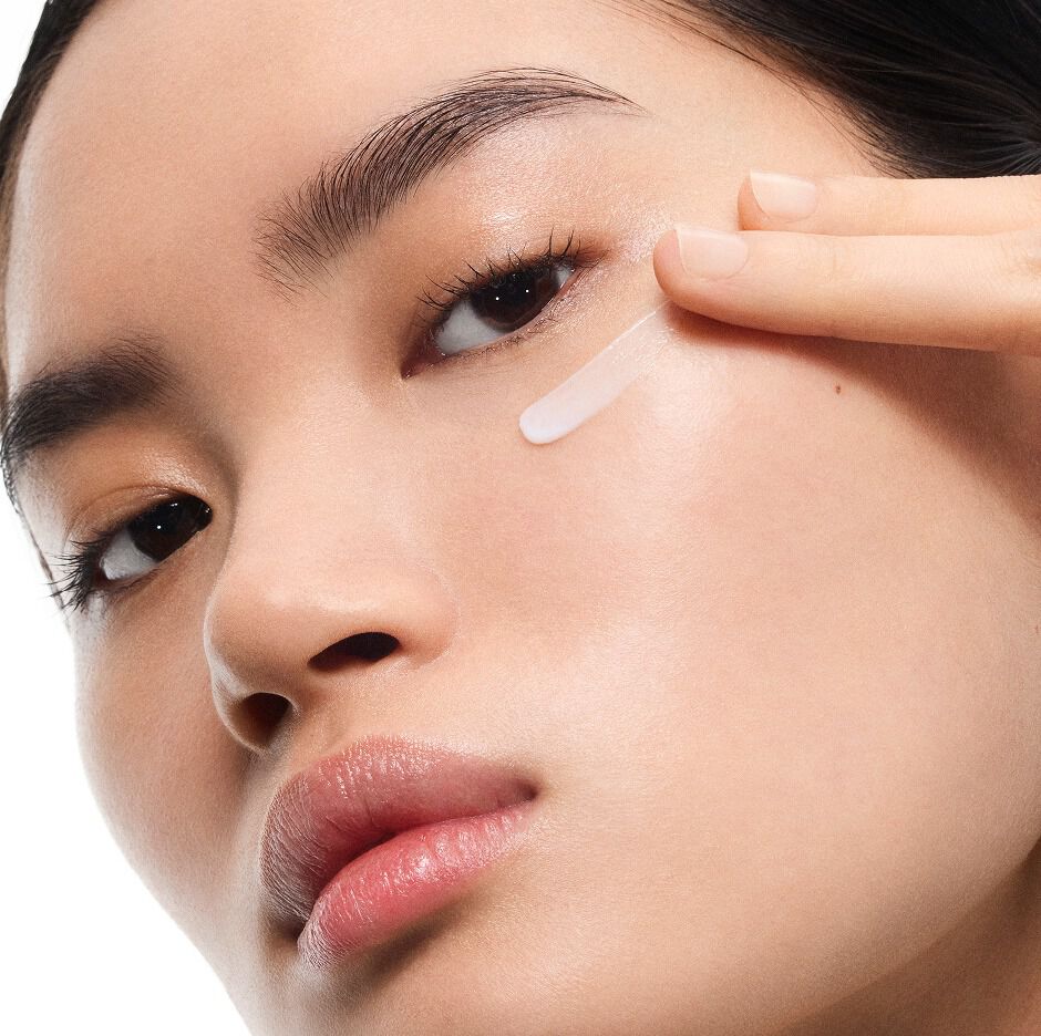 Model Mingma met een lichte huid brengt YSL Pure Shots Eye Reboot Cream aan onder haar oog, wat de delicate textuur laat zien.
