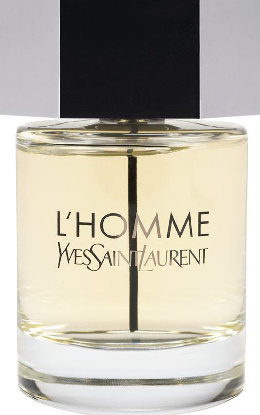 Een flacon van Yves Saint Laurent L'Homme parfum met een heldere glazen flacon, licht amberkleurige vloeistof en een grote zilveren zeshoekige dop.