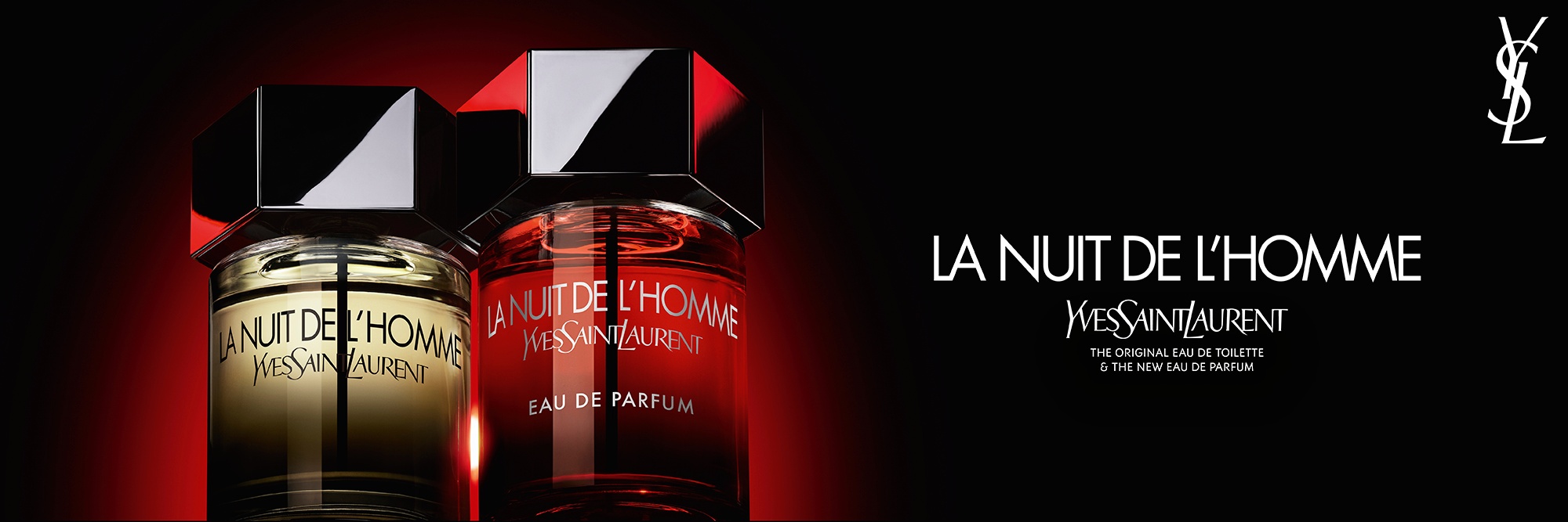 Een dramatische opname van de La Nuit de l’Homme Eau de Toilette en Eau de Parfum flacons naast elkaar, waarbij de klassieke amberkleurige vloeistof contrasteert met het nieuwe intense rode kleurverloop.
