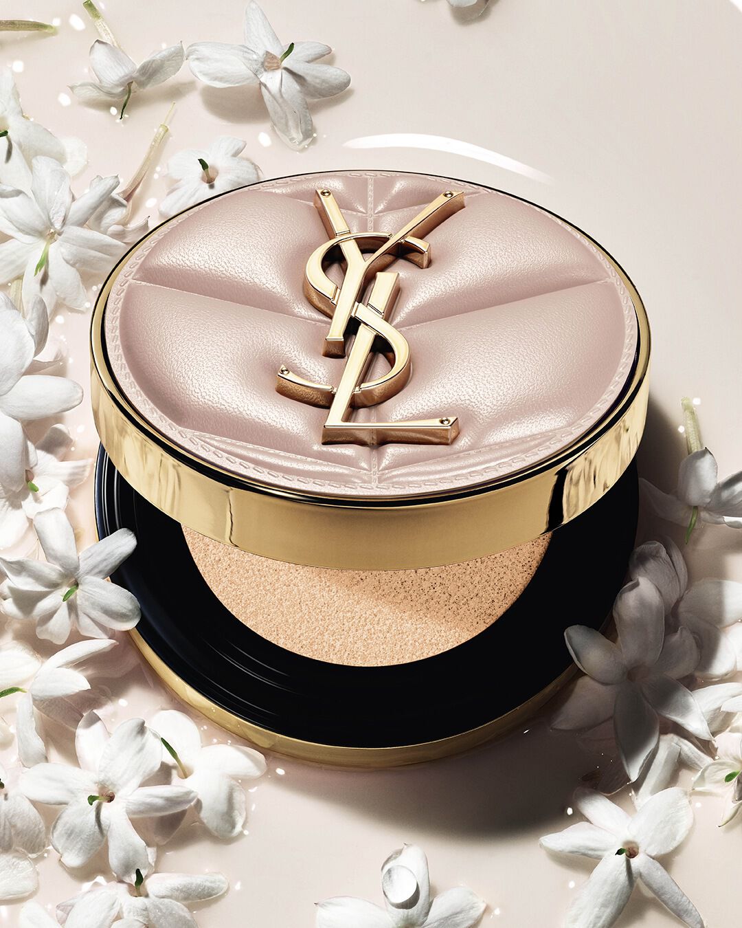Close-up van YSL SKIN AFFAIR SOFT GLOW CUSHION in een poel van vloeibare foundation en jasmijnbloemen. Stralende, sensoriële finish.