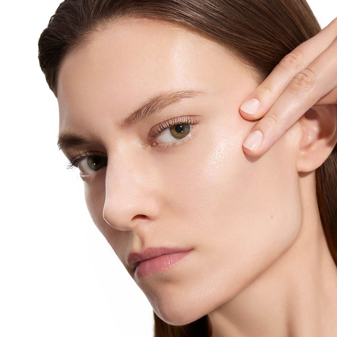 Marije, YSL Beauty-model, met een lichte huid, die voorzichtig haar wang aanraakt en gladde huid toont na het aanbrengen van lotion.