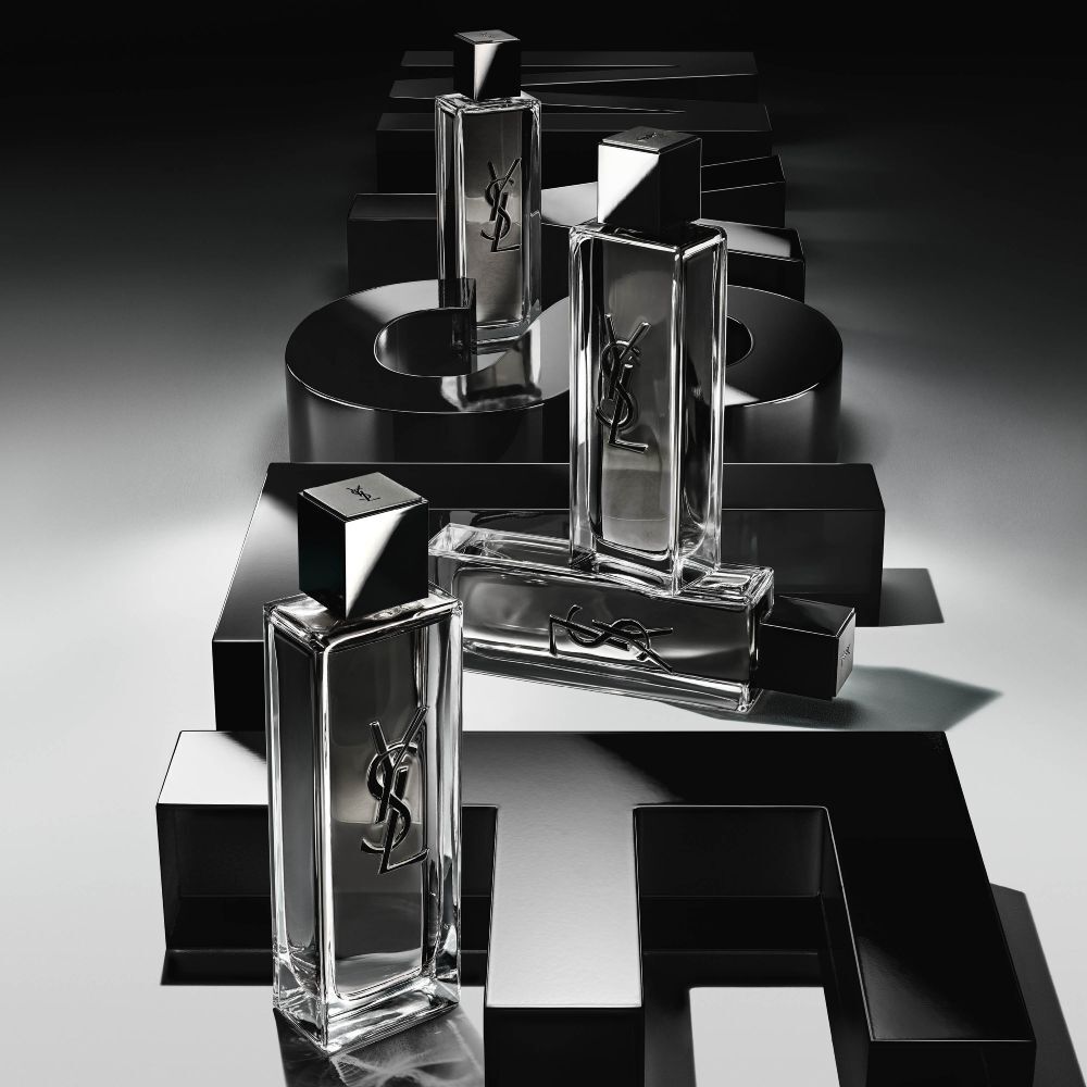 Bovenaanzicht van meerdere MYSLF Eau de Toilette Intense-flacons die zijn gerangschikt op grote zwarte 3D-letters die plat op de grond het woord MYSLF vormen.