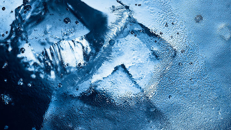 Close-up van ijs en waterdruppels, die de intense, ijzige frisheid van YSL Y Eau de Toilette Intense Iced Cologne oproepen.