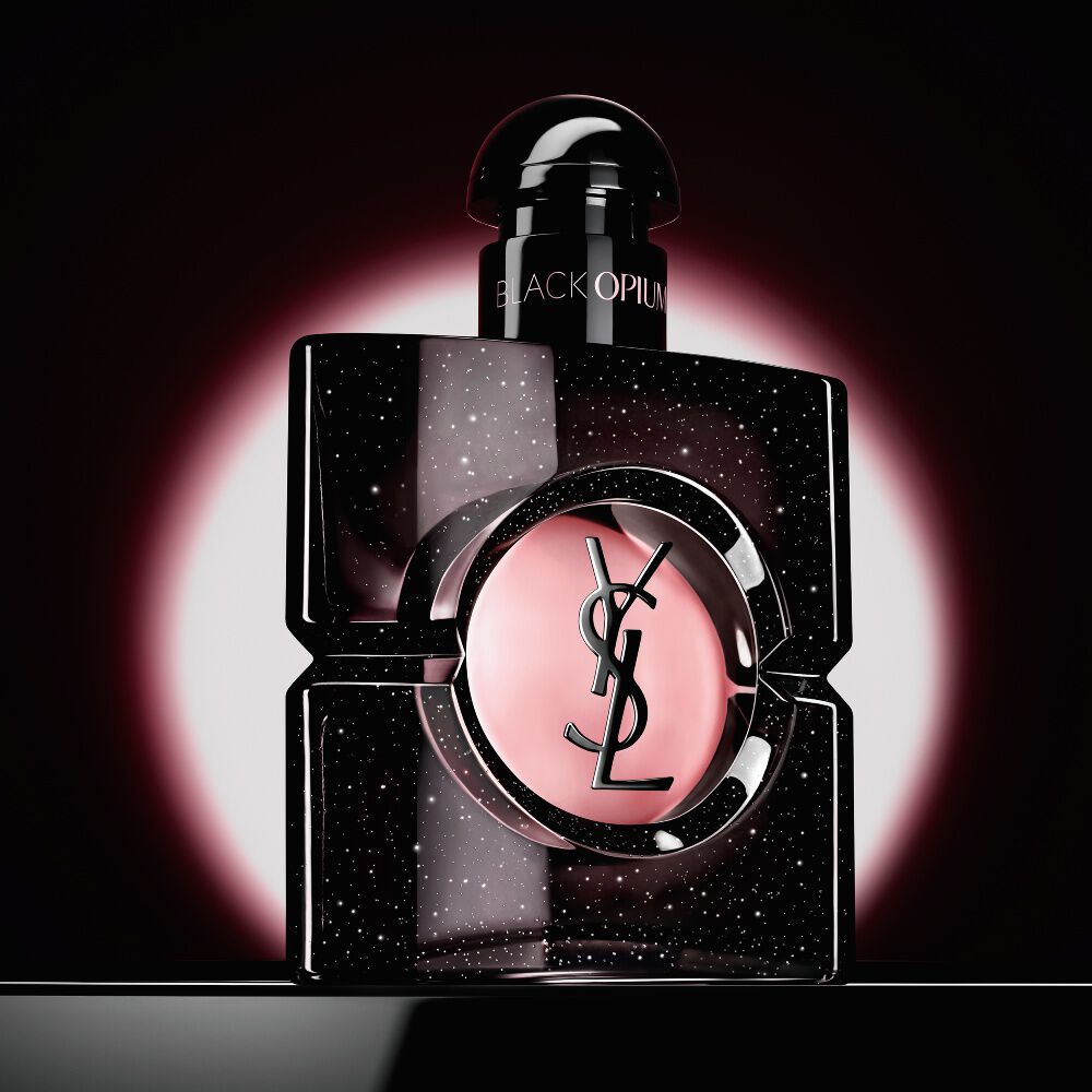 Black Opium Eau de Parfum-flacon, uitgelicht door een roze ronde gloed tegen een donkere achtergrond.